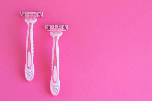 Dos maquinillas de afeitar rosadas sobre un fondo rosado. Navaja de afeitar para la higiene personal para la depilación - Foto, Imagen