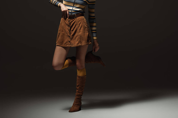 cropped view of young woman in autumnal outfit and boots standing on black - Foto, afbeelding