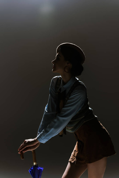 siluetti nuori nainen baskeri ja syksyn asu tummanharmaa tausta  - Valokuva, kuva