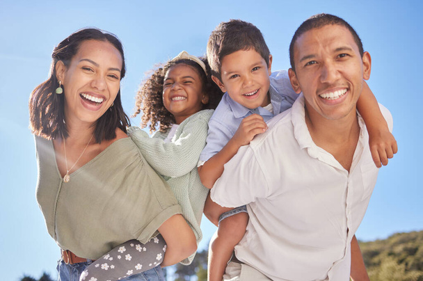 幸せな家族の肖像画、両親の子豚バックと父親と青空の屋外公園で一緒に笑顔。かわいい子供たちと若い母親、楽しい日差しの幸福と美しい夏ブラジルの休日. - 写真・画像