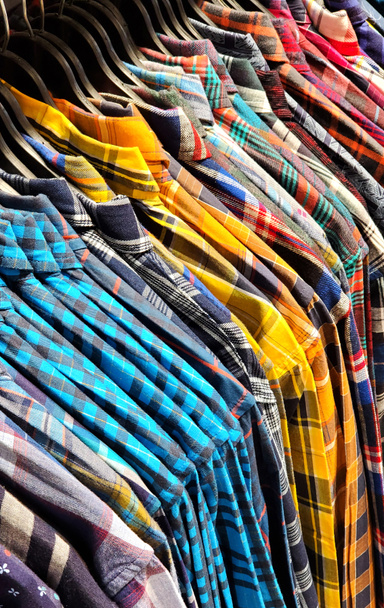 Крупный план мужских рубашек, висящих на вешалках в витрине магазина - Фото, изображение
