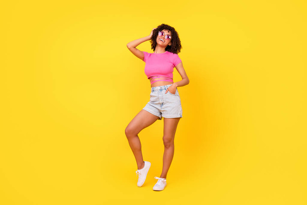 Full length photo of cute sweet lady wear pink top dark eyewear laughing empty space isolated yellow color background. - Foto, Imagem
