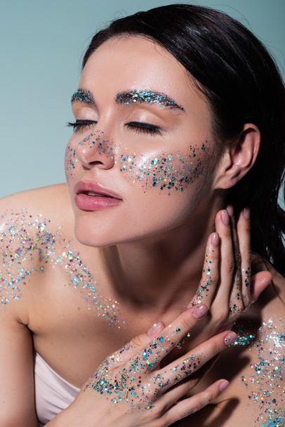 high angle view of young woman with glitter on face and body isolated on grey  - Foto, Imagem