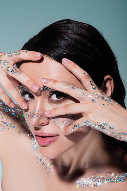 high angle view of young woman with glitter on face and body posing isolated on grey  - Foto, immagini