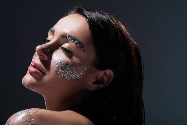 portrait of young woman with closed eyes and glitter on eyebrows isolated on grey - Fotografie, Obrázek