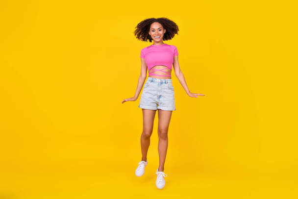 Full body portrait of overjoyed carefree girl jumping have good mood isolated on yellow color background. - Foto, Imagem