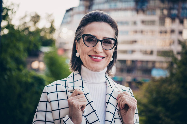 Photo of sweet shiny lady dressed checkered blazer eyewear smiling enjoying sunny weather outdoors urban town street. - Foto, Imagen
