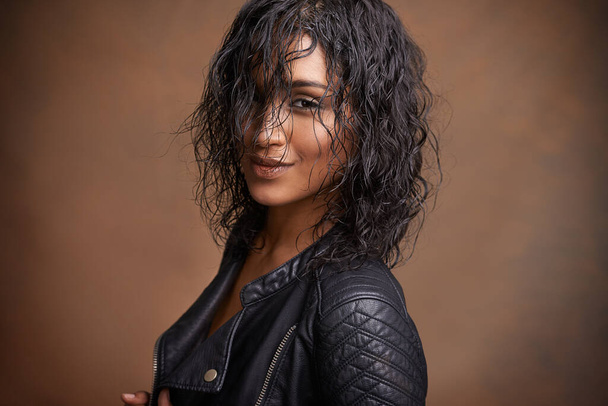 Stile pelle. Studio girato di una giovane donna attraente in una giacca di pelle su uno sfondo marrone - Foto, immagini