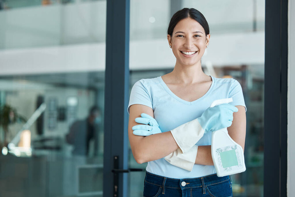 Cleaning service, portrait and cleaner in an office with spray bottle of disinfectant, bleach or detergent. Happy, smile and young female worker with gloves and soap liquid done washing glass windows. - Photo, Image