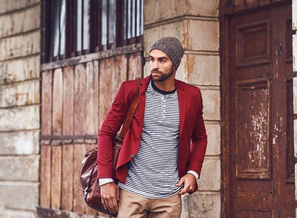 Zawsze w ruchu z klasą. przystojny młody mężczyzna w czerwonej kurtce spacerujący po ulicach niosąc torbę - Zdjęcie, obraz