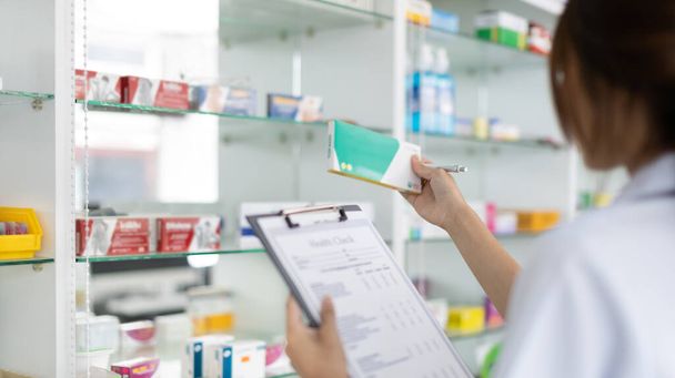 Pharmacist women are supplying prescription drugs to customers, Pharmacists work in a pharmacy, Drug store shelf with prescription medication, Clipboard at the hospital pharmacy, Community Pharmacy. - Foto, imagen