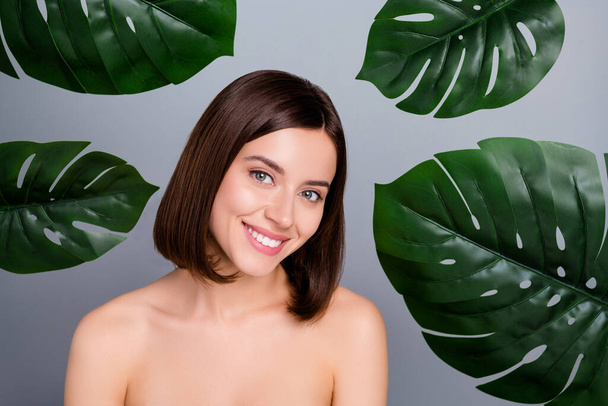 Photo of joyful girlish lady stand green leaves skin care peeling lifting treatment isolated over grey color background. - Foto, afbeelding