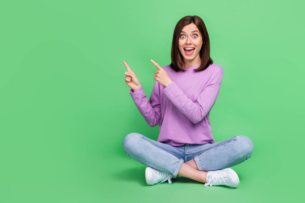 Full length photo of young pretty gorgeous nice woman wear purple pullover crazy fingers pointing empty space advert deal isolated on green color background. - Foto, Imagen