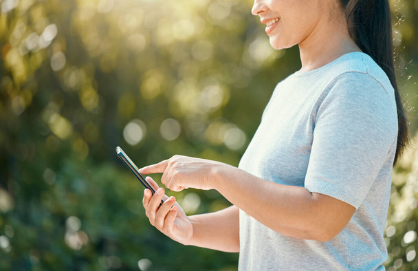 Woman, phone and nature park while touching screen for mobile app, communication for sustainability and environment management tool. Hand of female with 5g network and technology connection outside. - 写真・画像