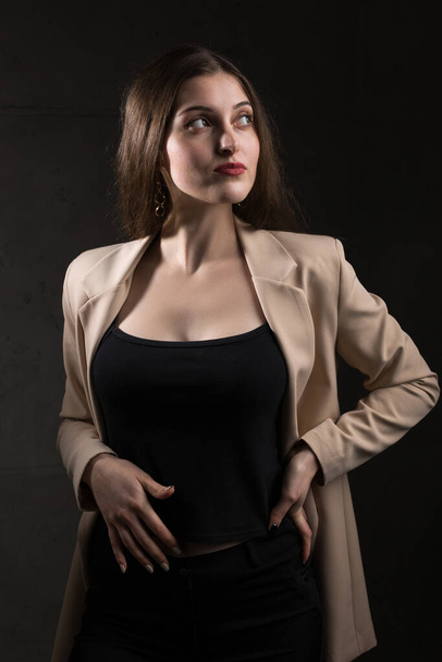 Portrait of a young brunette with long hair in the studio. Dramatic photo in dark colors. - Fotó, kép