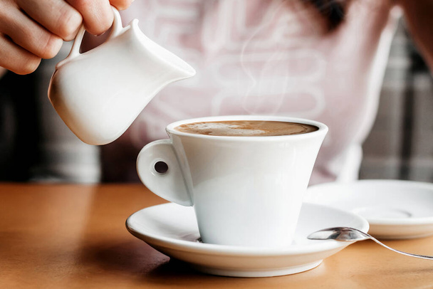 Goedemorgen koffie. Sluiten van vrouwenhanden met koffiekop in een café. Vrouwelijke handen houden kopjes koffie op een houten tafel achtergrond in een cafe, vintage kleur toon - Foto, afbeelding