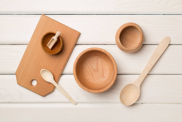 Wooden cutlery, bowls and board on wooden background, top view. - Fotografie, Obrázek