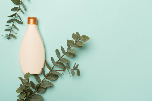 Kosmetikflasche mit Eukalyptuszweig auf farbigem Hintergrund, Draufsicht. - Foto, Bild