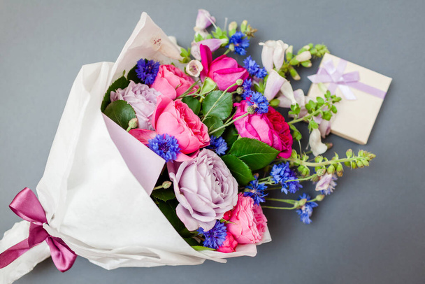 Gros plan du bouquet de roses foxgloves boutons de célibataire fleurs enveloppées dans du papier avec boîte cadeau. Présent pour les vacances. Vue du dessus - Photo, image