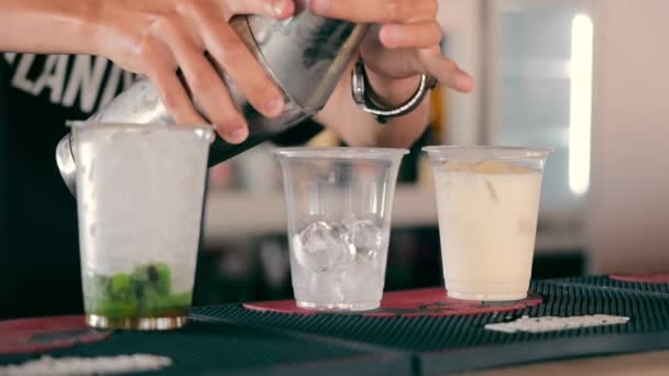 Un camarero hace un cóctel con hielo de cerca en una taza desechable. Un cóctel en un recipiente de plástico. - Metraje, vídeo
