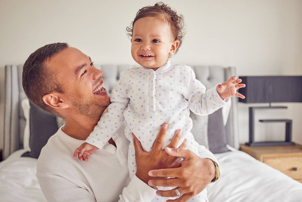 A happy dad and baby with smile on the bed at home, having fun and laughing together. Portrait of man bonding, smiling and playing with kid in bedroom. Family, love and care from father. - Фото, зображення