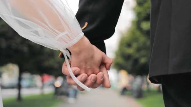 man en vrouw hand in hand tijdens het lopen in de stad close-up. Een man en een vrouw houden elkaar stevig vast tijdens het lopen.. - Video