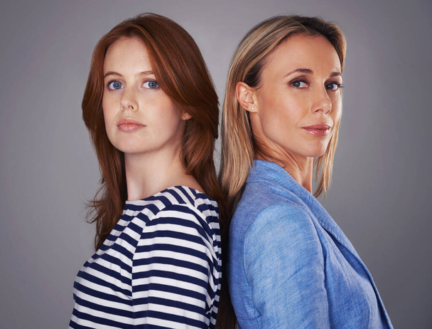 Weve got each others back. Cropped portrait of two attractive women standing back-to-back in the studio - Photo, Image