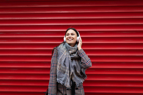 portrait d'une jeune femme joyeuse dans un casque sur fond de mur rouge en relief. - Photo, image