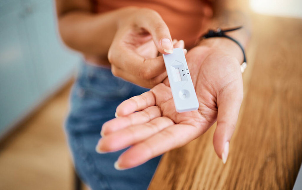 Woman hands holding a covid test for safety, healthcare and medicare with a negative result. Closeup of a rapid coronavirus antigen testing kit for a medical diagnosis exam with a pcr device at home - Foto, Imagem