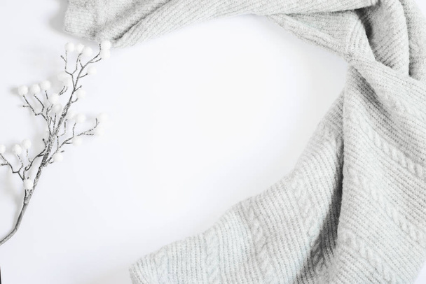Grauer Pullover und weißer Ast auf weißem Hintergrund, Platz für Text. Kopierraum. Winter minimalistische flache Lage, Draufsicht - Foto, Bild