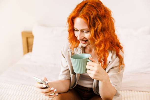 Young woman working from home via telephone and holding a cup of coffee. High quality photo - Photo, image