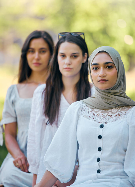 Muzułmanin, islam i moda z islamską kobietą siedzącą na zewnątrz z przyjaciółmi w kolejce w ciągu dnia. Religia, wiara i wiara z arabską kobietą na świeżym powietrzu z rzędu z grupą przyjaźni. - Zdjęcie, obraz