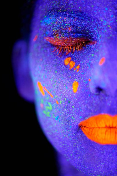 Képzelj el egy fiatal nőt neon festékkel az arcán. - Fotó, kép