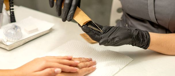 O mestre de manicura tira instrumentos de manicura de um envelope de kraft em um salão de beleza de prego - Foto, Imagem
