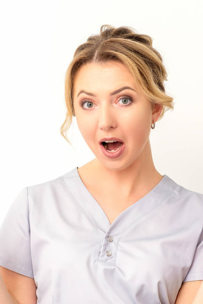 Jovem surpreso mulher branca médico ter chocado expressão abrindo a boca contra o fundo branco - Foto, Imagem