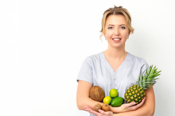 白い背景の上に彼女の手の中に異なる果物と若い白人女性栄養士の肖像画 - 写真・画像