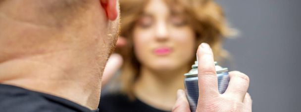 Kampaaja käyttää hiuslakkaa korjata kampauksen nuori valkoihoinen nainen kampaaja salonki, lähikuva - Valokuva, kuva