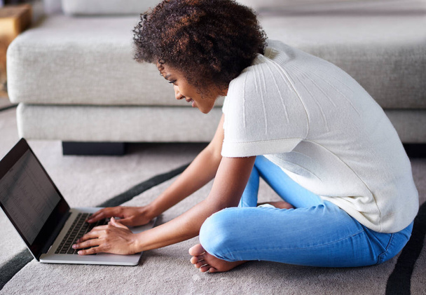 Ze raakt opgewonden over dat online winkelen... een jonge vrouw die haar laptop gebruikt terwijl ze thuis op de vloer zit. - Foto, afbeelding