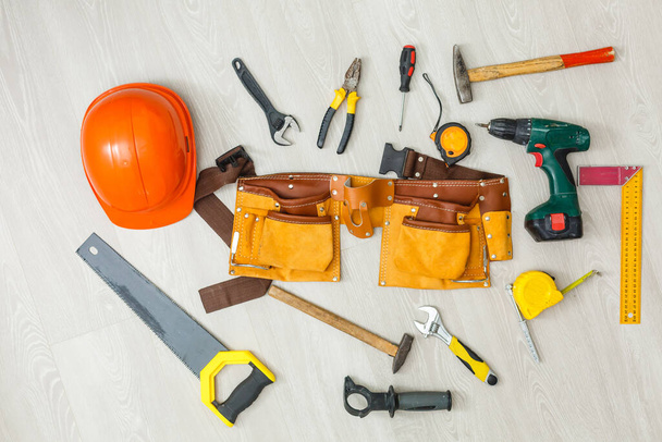 Conjunto de herramientas de construcción en correa de herramientas de primer plano en tablero de madera
 - Foto, imagen