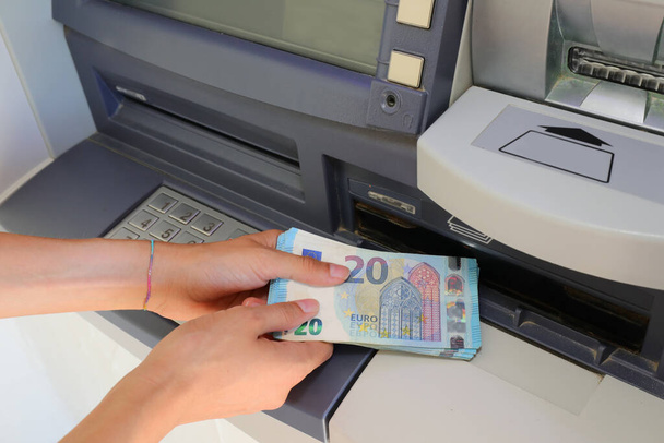 ヨーロッパのATM銀行の現金機からヨーロッパの銀行券でお金を拾う手 - 写真・画像