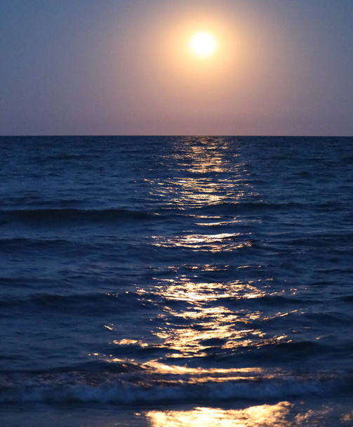 gran círculo de luz en la noche y la reflexión sobre el agua plácida del océano - Foto, imagen