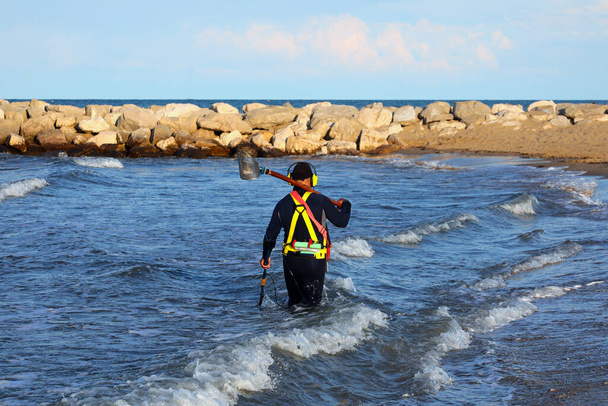 Pesquisador homem branco recuperando itens perdidos no mar na praia com terno de mergulho no verão - Foto, Imagem