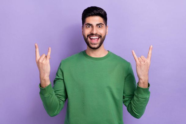 Fotografie pohledný stylový dojem neopatrný chlap nosit zelený svetr ukazující rohy těžký kov izolované na fialovém pozadí. - Fotografie, Obrázek