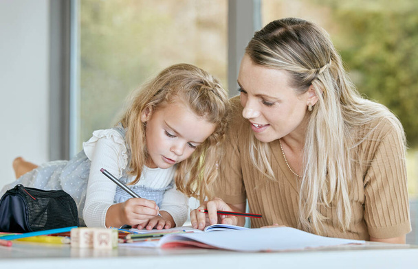 Mütter helfen jungen Mädchen bei Schularbeiten, Hausaufgaben oder Vorschulerziehung, während sie in Notizbüchern schreiben. Mutter hilft, unterrichtet oder lehrt Tochter, Studentin oder junges Lernkind in Mathe, Geschichte oder Englisch. - Foto, Bild