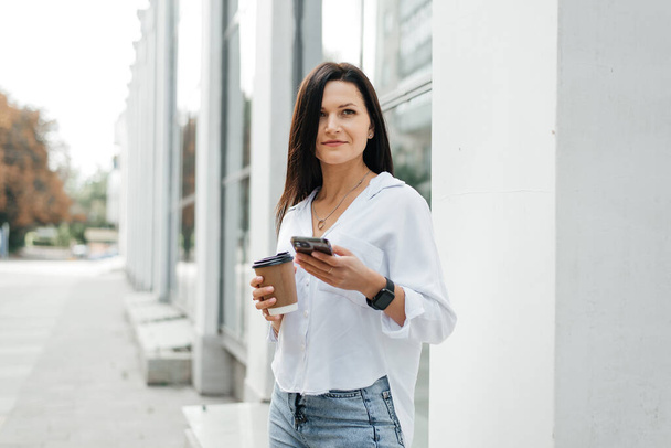 giovane donna moderna con telefono e caffè per strada - Foto, immagini