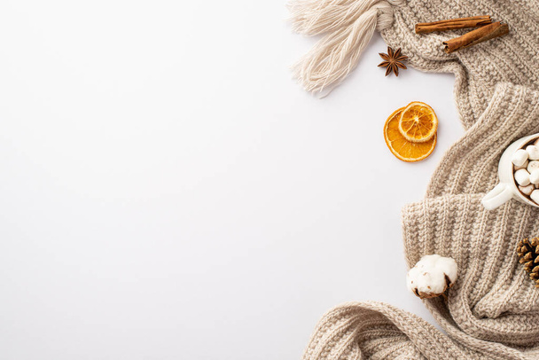 冬のコンセプト。マシュマロ乾燥オレンジスライスとココアのニット再生カップのトップビューの写真コピースペースと隔離された白い背景にシナモンスティック綿の花と松のコーン - 写真・画像