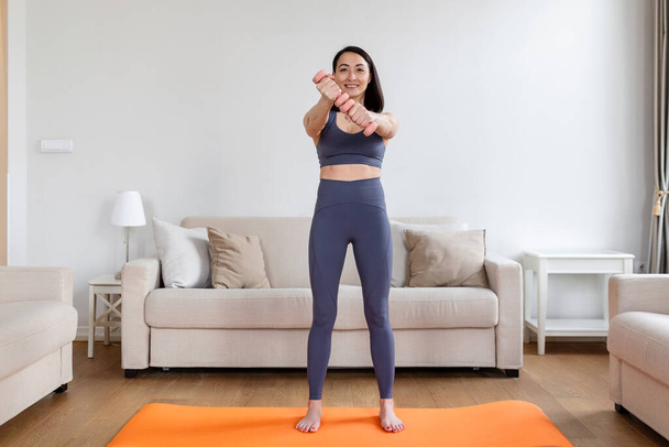 Mujer asiática haciendo ejercicio con pesas en casa. Mujer feliz haciendo ejercicio de brazo usando pesas - Foto, Imagen
