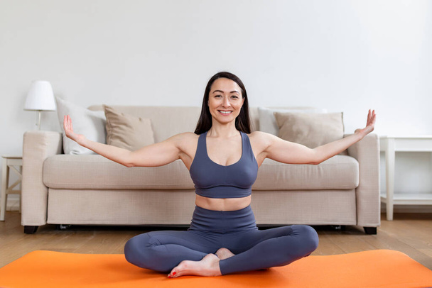 Ázsiai nő otthon edz, nyújtózkodik. Ideje jógázni. Vonzó és egészséges fiatal nő gyakorolja, miközben otthon pihen. fiatal nő gyakorló otthon, belső - Fotó, kép
