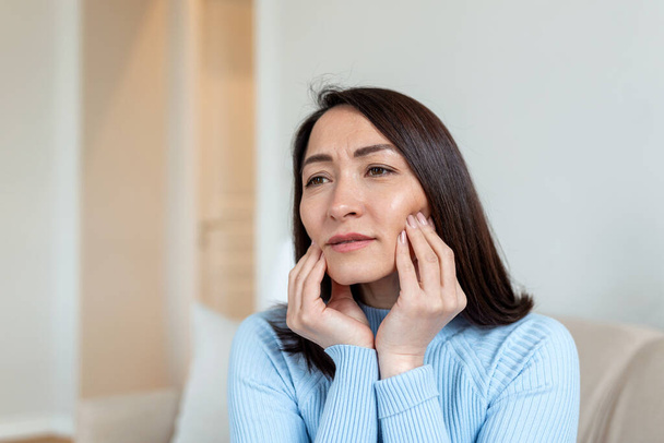 Portrait of unhappy Asian woman suffering from toothache at home. Healthcare, dental health and problem concept. Stock photo - Fotografie, Obrázek