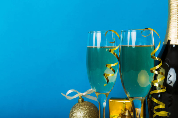 Пляшка шампанського з конфетті, окулярами та різдвяним декором на кольоровому фоні свята. Плоскі новорічні прикраси
. - Фото, зображення